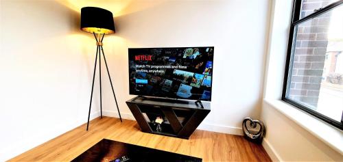 a living room with a flat screen tv and a lamp at Cliftonville Heights - 2 bed Home away from Home in Northampton