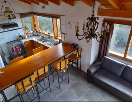 a kitchen with a bar with chairs and a couch at Casa luminosa entre montañas in San Carlos de Bariloche