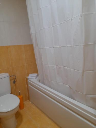 a bathroom with a toilet and a bathtub with a shower curtain at ALOJAMIENTO LOS DINOSAURIOS in Cuenca