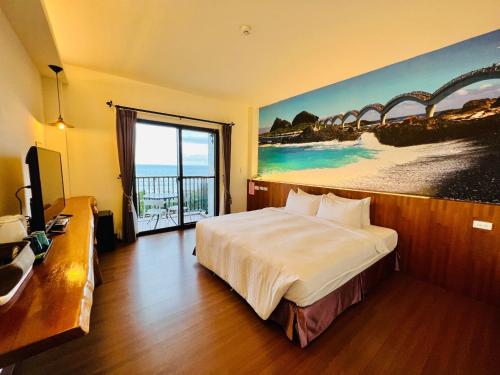 成功的住宿－台東嵐海民宿，酒店客房设有一张床,墙上挂有绘画作品