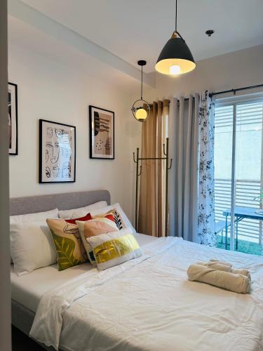 um quarto com uma cama branca e uma janela em Scandinavian 1 BR beside SM CDO w POOL and Netflix em Cagayan de Oro