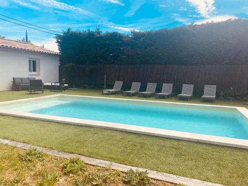 une piscine dans une cour avec des chaises autour dans l'établissement La Maison d à côté 8 à 10 personnes, à Carpentras