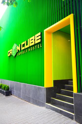 a green building with a yellow door and stairs at Green Cube Capsule Hostel in Sofia