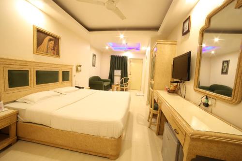 a bedroom with a bed and a sink and a mirror at Hotel Samrat International in Mount Ābu