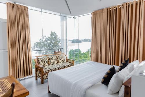 a bedroom with a bed and a chair and a large window at Centhara Beach Weligama in Weligama