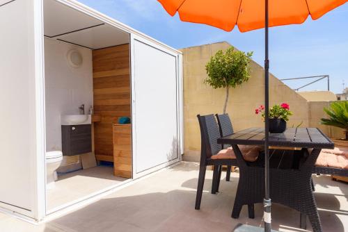 eine Terrasse mit einem Tisch und einem Sonnenschirm in der Unterkunft Casa Deguara townhouse Rabat Malta in Rabat