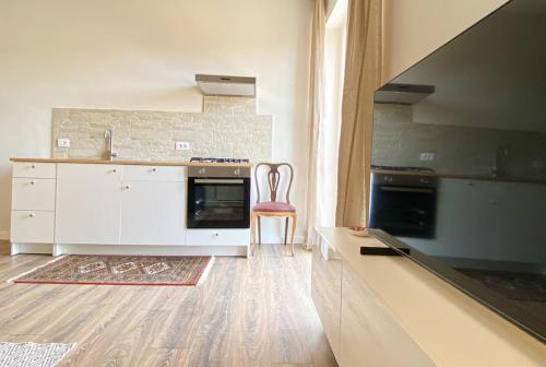 a kitchen with white cabinets and a red chair at CasaJila in Novi Ligure