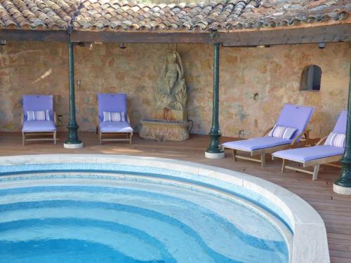 uma grande piscina com cadeiras azuis e uma casa em Apartment Cézanne mit geheiztem Pool und Privatgarten em Châteauneuf