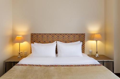 a bedroom with a large white bed with two lamps at GINGER Hotel in Tbilisi City