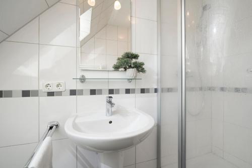 uma casa de banho branca com um lavatório e um chuveiro em Haus Waidmannsruh Hubertus em Kellenhusen