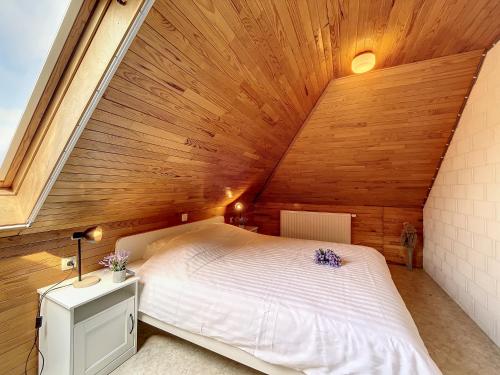 ein Schlafzimmer mit einem großen Bett in einer Holzdecke in der Unterkunft Villa Maurice close to the beach in Oostduinkerke