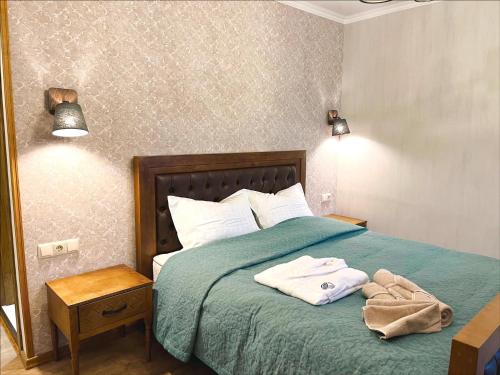 a bedroom with a green bed with towels on it at VinoOdor - ვინოოდორ in Tʼelavi