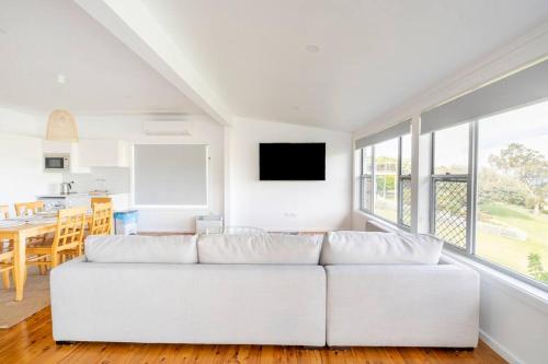 uma sala de estar branca com um sofá branco e uma mesa em Kiama Beach House & Private Beach & Newly Renovated em Kiama