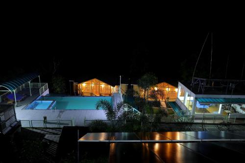 a house with a swimming pool at night at Woodrose Resort in Kalpetta