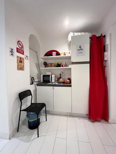 a small kitchen with a red curtain and a refrigerator at GladiatoRooms Rome - Colosseo in Rome