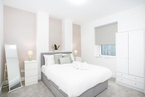 um quarto branco com uma cama grande e um espelho em Beach Walk by Sorted Stay em Southend-on-Sea