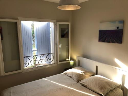 um quarto com uma cama e uma grande janela em Mas le Pénéquet em Aubignan
