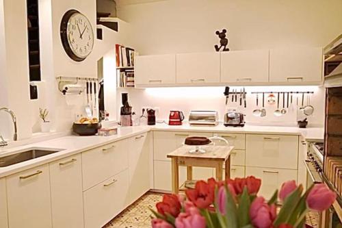 eine Küche mit weißen Schränken und rosa Tulpen in der Unterkunft Jolie maison de ville à 5 minutes de Paris pour 5 voyageurs parking inclus in Clichy