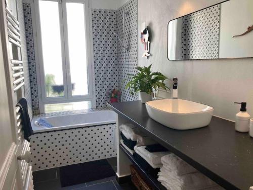une salle de bain avec un lavabo et une baignoire dans l'établissement Jolie maison de ville à 5 minutes de Paris pour 5 voyageurs parking inclus, à Clichy