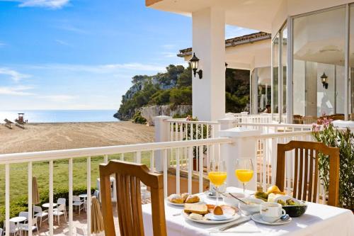 - une table avec de la nourriture et des boissons sur un balcon donnant sur la plage dans l'établissement FlipFlop Cala Romántica, à Cala Romantica