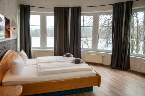 Schlafzimmer mit einem großen Bett vor den Fenstern in der Unterkunft Terrassenhotel Seepromenade in Edersee