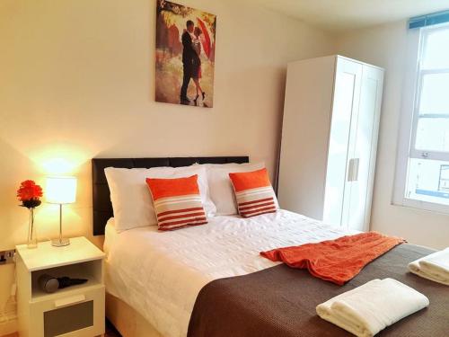 a bedroom with a bed with orange pillows on it at Comfortable Studio flat near Central London in London