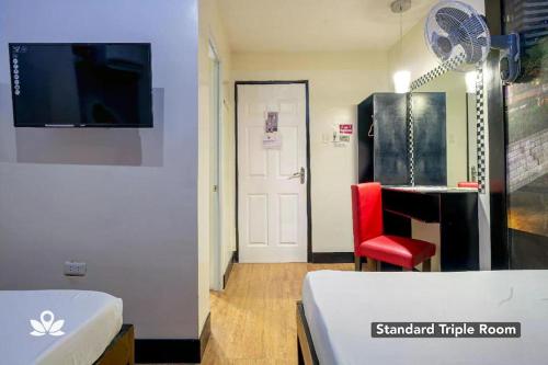 Habitación con cama, escritorio y silla roja. en Sabel Travelers Inn en Laoag