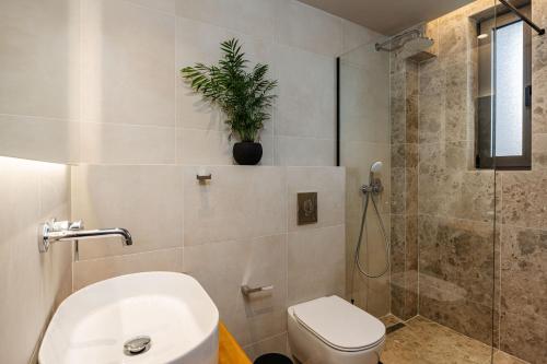 a bathroom with a toilet and a shower with a plant at Horizon Apartments - Beachfront Luxury, by ZanteWize in Laganas