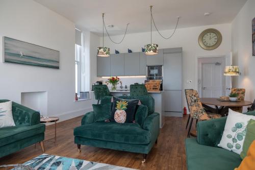 een woonkamer met groene stoelen en een tafel bij Rutland Heights in Torquay