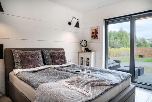 een slaapkamer met een bed en een glazen schuifdeur bij Domek hot tub jacuzzi Chillout in Kołobrzeg