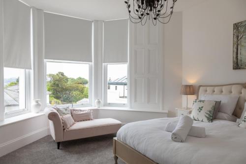 a bedroom with a bed and a chair and windows at Rutland Heights in Torquay