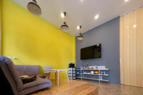 a living room with a yellow wall and a couch at Paknap Hostel in Nan