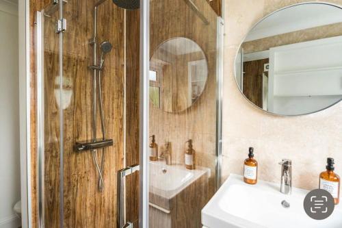 a bathroom with a shower and a sink and a mirror at Where Style & Convenience Combine- Photo ID Required in London