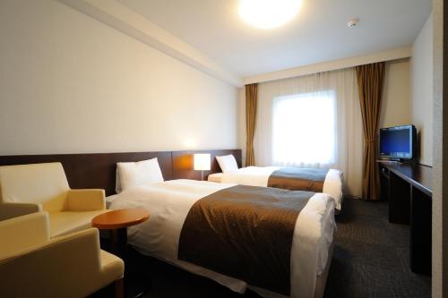a hotel room with two beds and a television at Dormy Inn Sendai Station Natural Hot Springs in Sendai