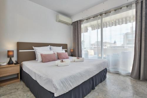 une chambre avec un grand lit avec une grande fenêtre dans l'établissement Cannes centre-Palais-200m des plages, à Cannes
