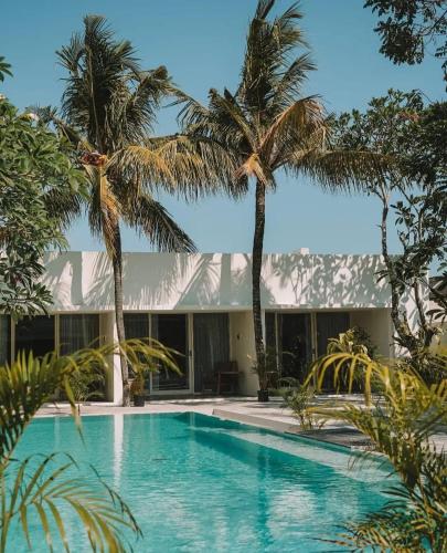ein Swimmingpool vor einem Haus mit Palmen in der Unterkunft Ayom Suite in Mataram