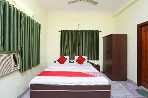 um quarto com uma cama com cortinas verdes e almofadas vermelhas em Honey Regency Near City Centre Salt Lake em Calcutá