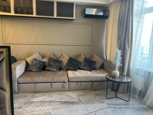 a living room with a couch with pillows and a table at Apart Elena Arcadia Sea View in Odesa