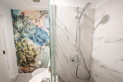 a bathroom with a shower with a mosaic wall at MyContinental Suceava in Suceava