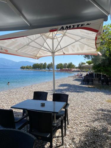 a table and chairs under an umbrella on the beach at Spiti Eutychia in Ayía Eléni