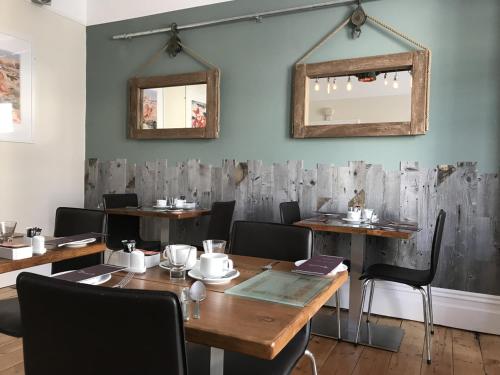 uma sala de jantar com mesas e cadeiras de madeira e espelhos em St Bernards em Newquay