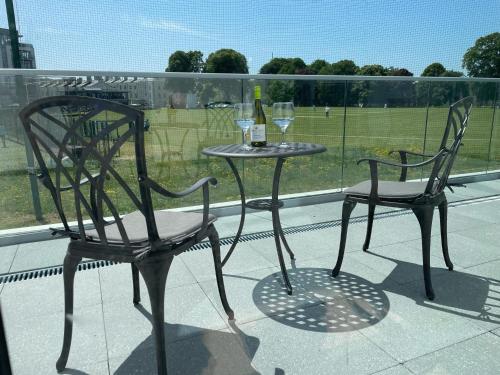two chairs and a table with wine glasses on a balcony at 3 Bed- The Pavilion By Pureserviced in Plymouth