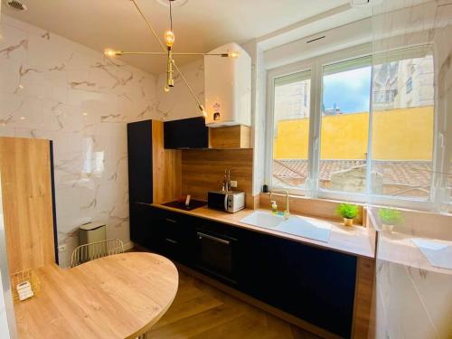 d'une cuisine avec un comptoir, un évier et une fenêtre. dans l'établissement ''Le Général'' Superbe appartement Haussmanien climatisé en coeur de ville, à Sète