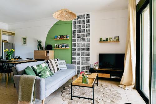 uma sala de estar com um sofá azul e uma parede verde em Oliva Holiday Homes em Dhiyeliótika