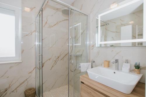a bathroom with a glass shower and a sink at Royal Blue House 3 in Kaštela