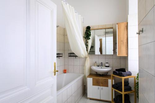ein weißes Badezimmer mit einer Badewanne und einem Waschbecken in der Unterkunft Infinity Homes - Stylish 3-Bedroom Haven in the Heart of Vienna! in Wien