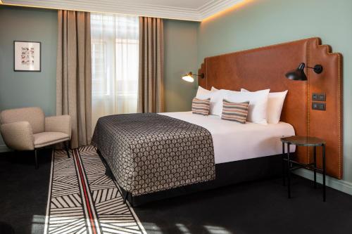 ein Hotelzimmer mit einem Bett und einem Stuhl in der Unterkunft Maison Rouge Strasbourg Hotel & Spa, Autograph Collection in Straßburg