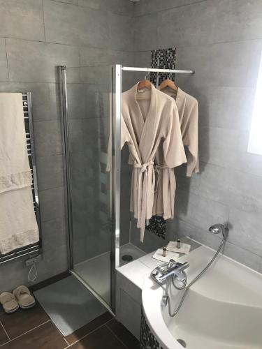 a bathroom with a shower and a sink and a robe at LA ROMANTIQUE SPA in Saint-Avertin