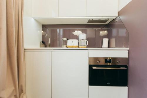 a kitchen with white cabinets and a black oven at Atlant luxury VIOLET Apart on Golovna стильні апартаменти поряд з ТЦ ДЕПОТ БЕЗКОНТАКТНЕ ЗАСЕЛЕННЯ in Chernivtsi