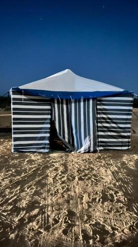 Mbiama Resort في سيوة: خيمة زرقاء وبيضاء على شاطئ رملي